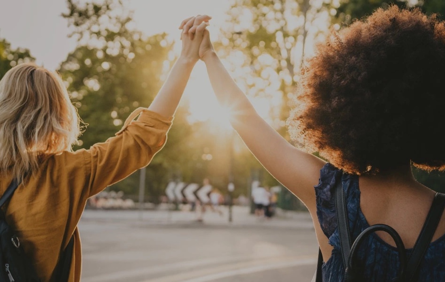 Viewed from behind, two women lifting their interlocked hands 