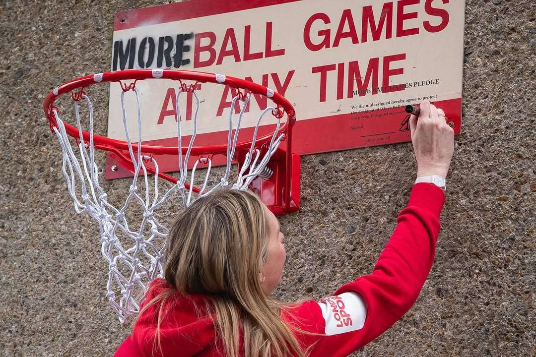 Basketball hoop attached to a sign rewritten to read 'More ball games at any time' 
