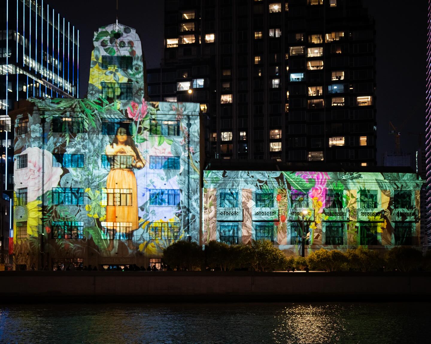 Huge projection of an artist communicating in sign language, surrounded by flowers, on an Art Deco building 