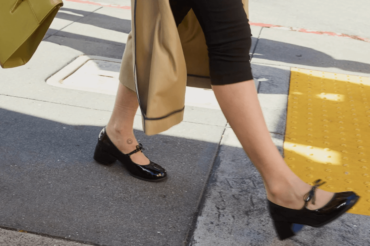 Two legs in glossy black shoes walking by 